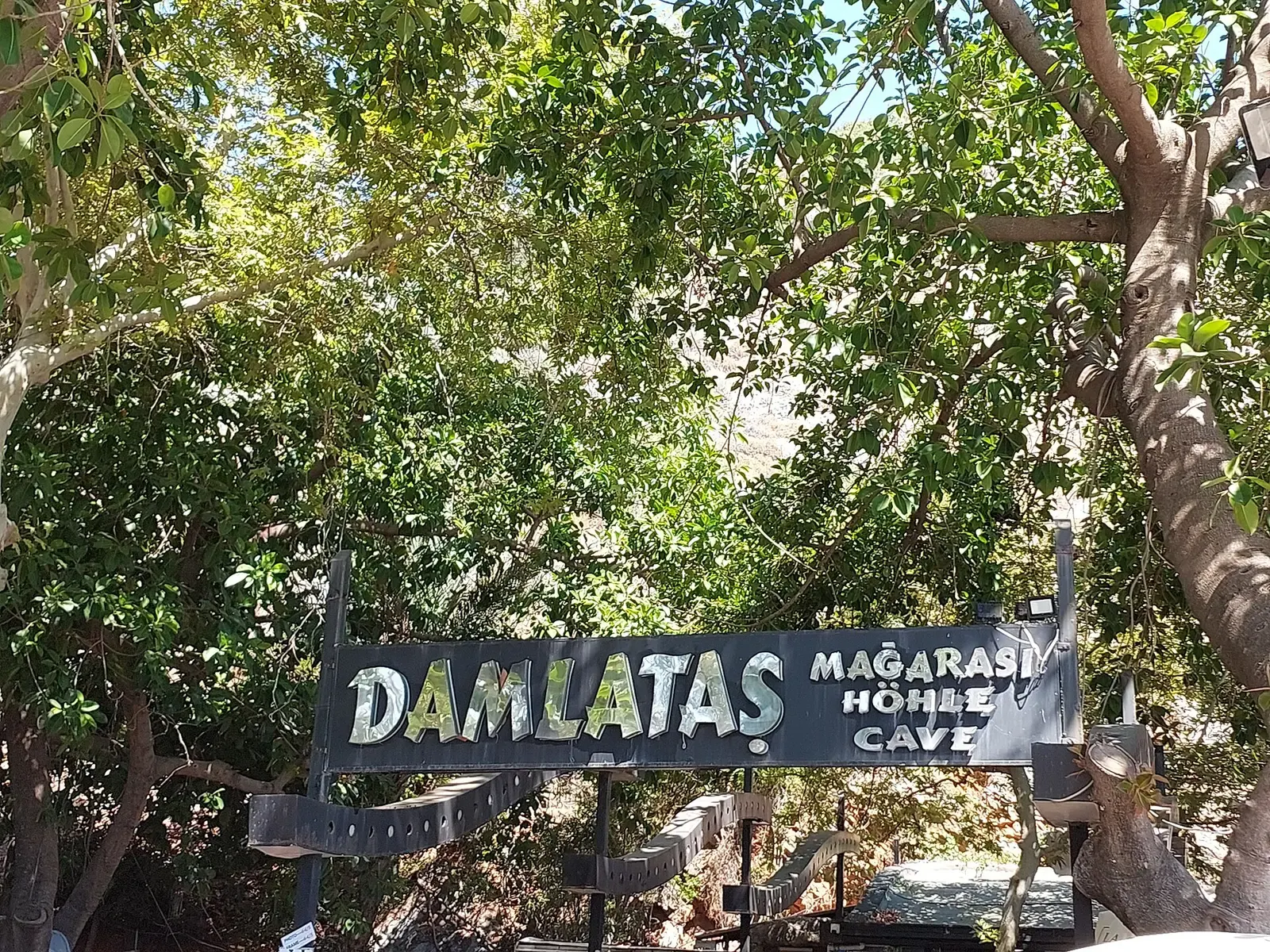 De ingang van de Damlataş grot onder de bomen vlak bij het strand van Alanya