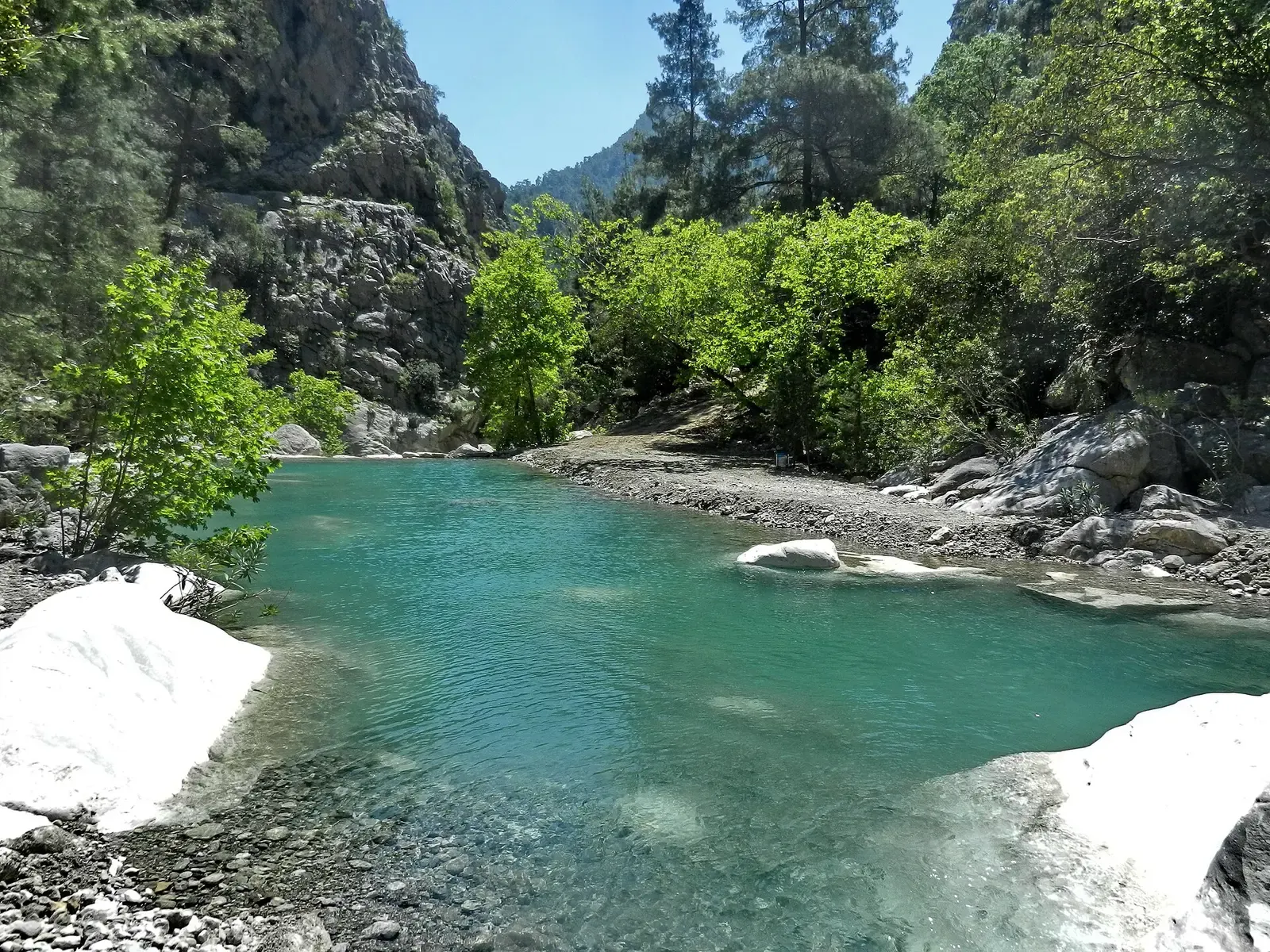 Een helderblauwe poel tussen rotsen en bomen in de Göynük kanyon