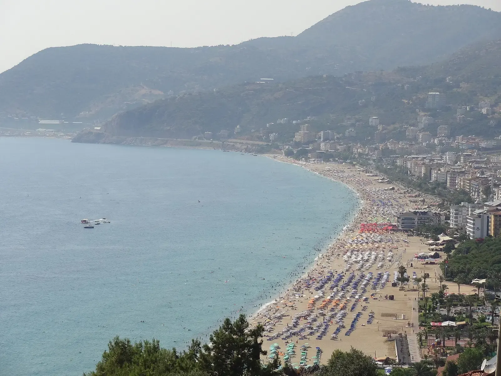Het Kleopatrastrand van Alanya met rijen parasols langs de gebogen baai, gezien van bovenaf