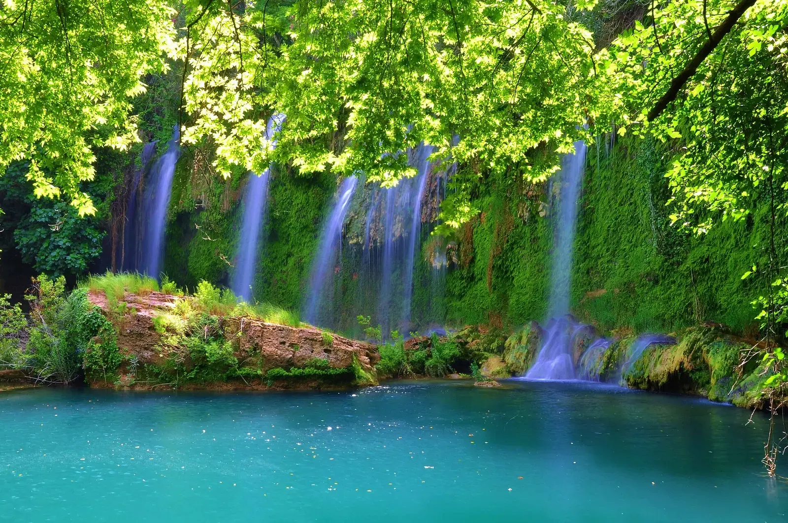 De Kurşunlu waterval die in een turquoise poel valt onder het groene bladerdak