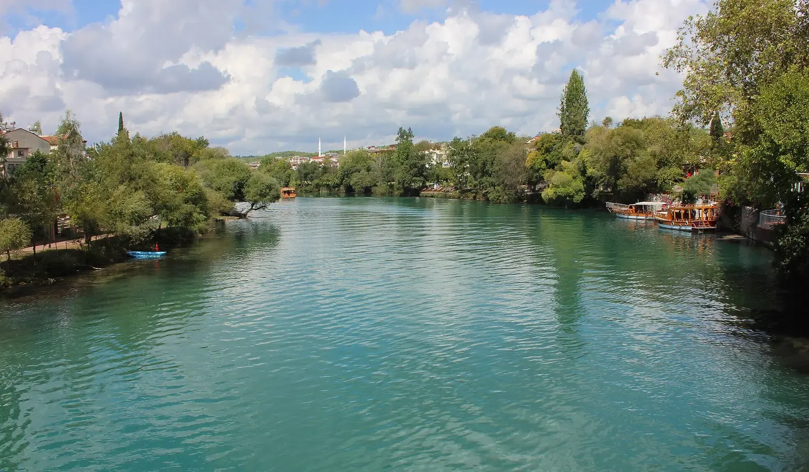 De groenblauwe Manavgat rivier tussen begroeide oevers in de stad Manavgat