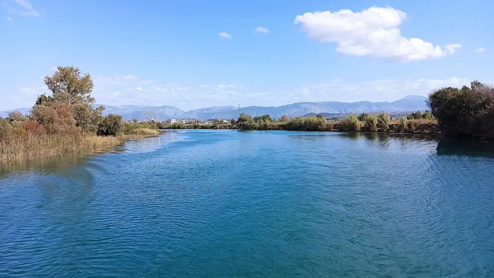 De brede Manavgat rivier met rietkragen en de bergen in de verte