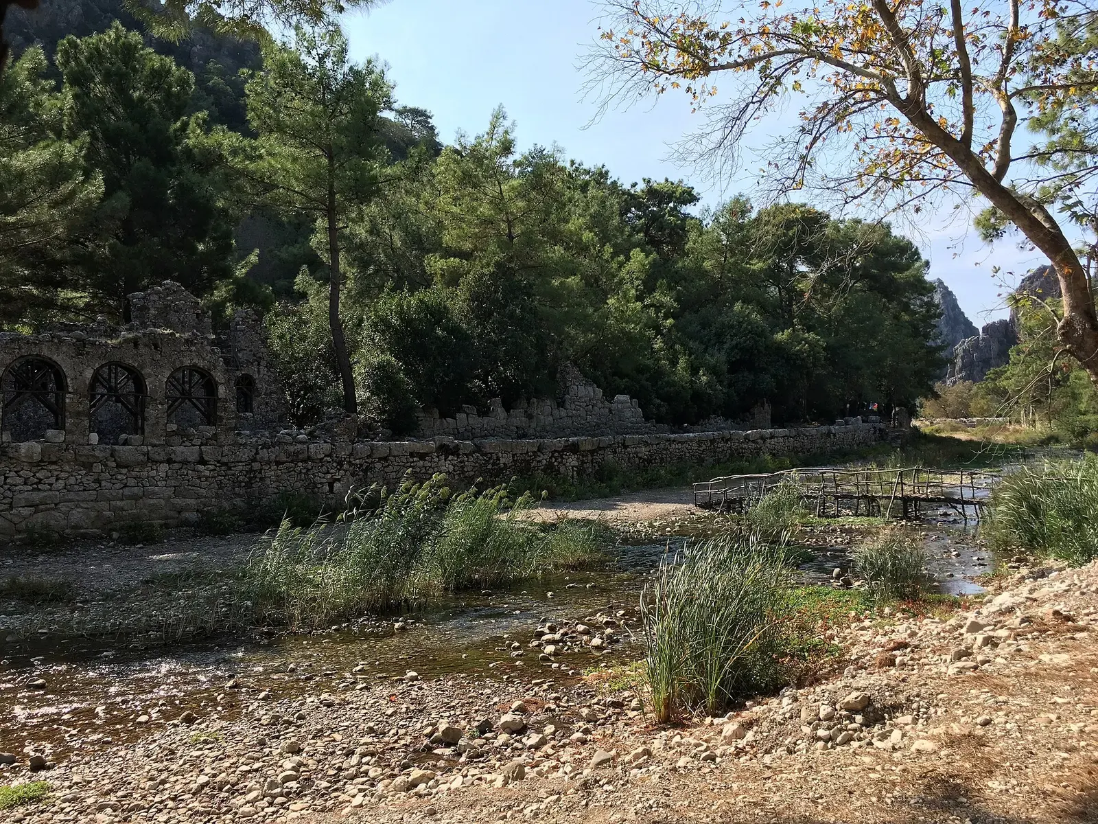 De beek door Olympos met ruines van een gebouw met bogen aan de oever